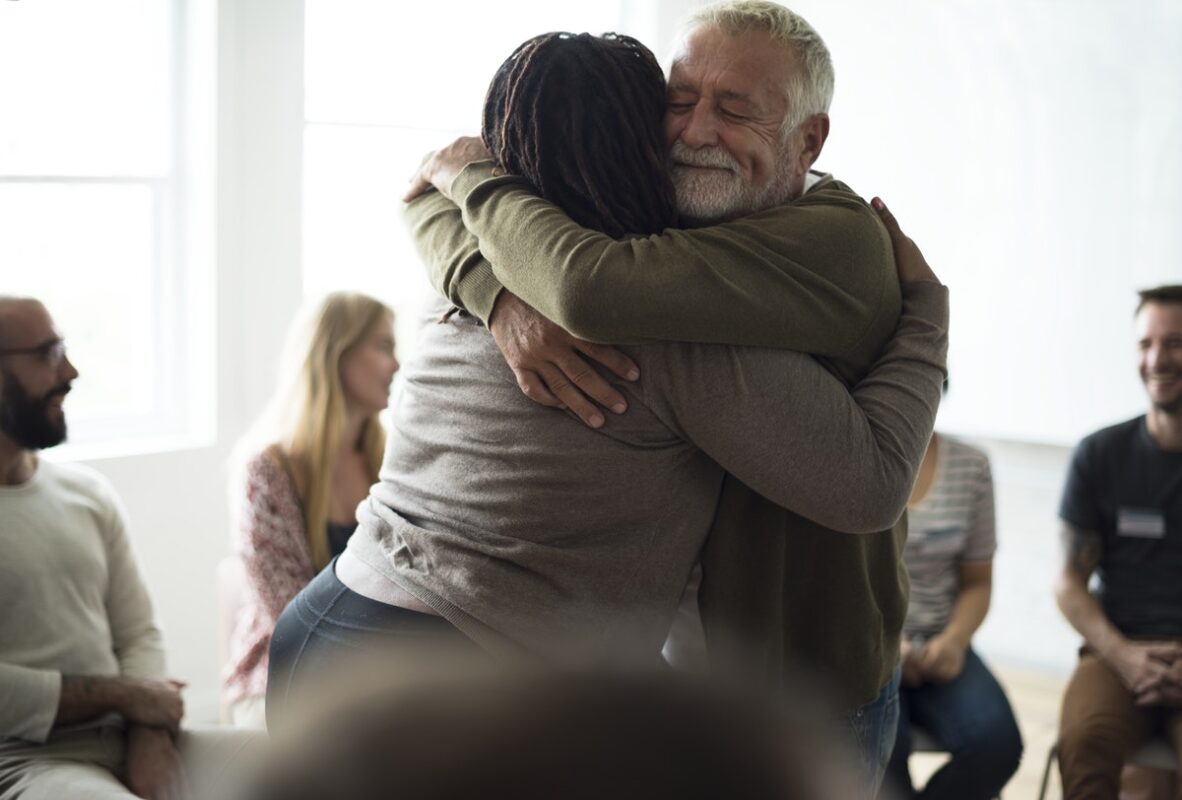 Senior man hugging woman in support group