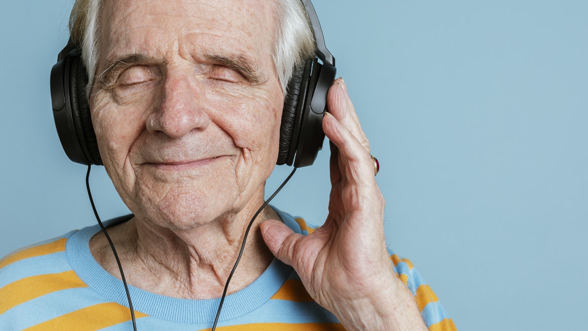 Happy senior man listening to music with headphones