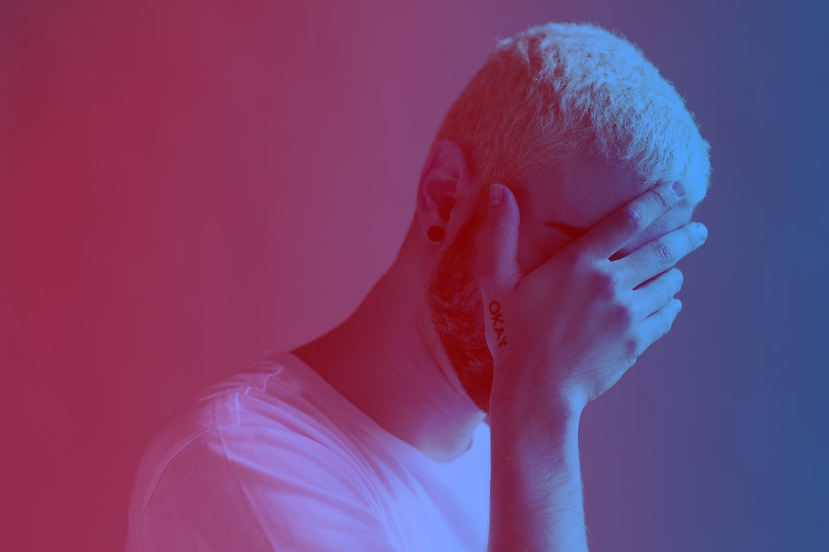 Depressed man covering his face red filter effect