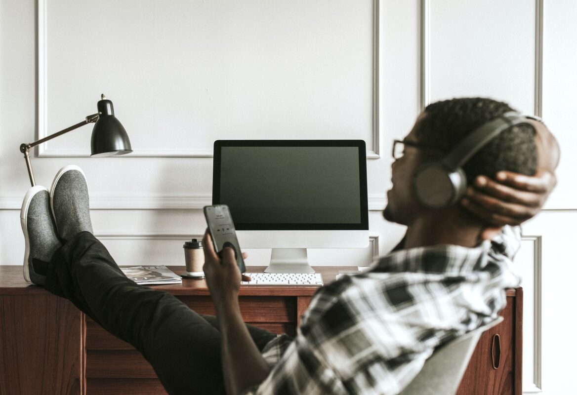 man with headphones playing on his phone sitting at his desk